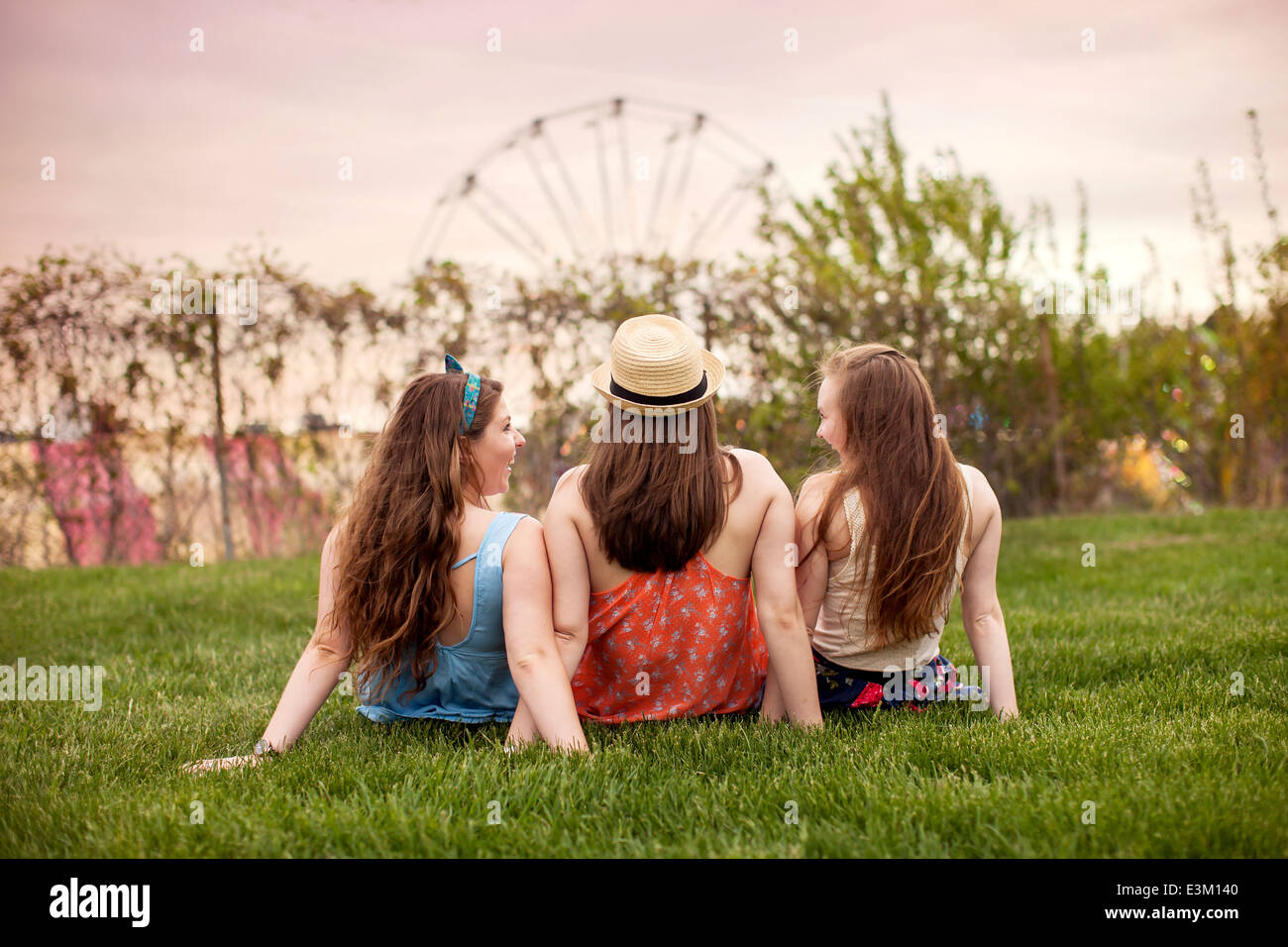 Rückseite Blick auf drei junge Frauen (18-19) sitzen auf dem Rasen Stockfoto