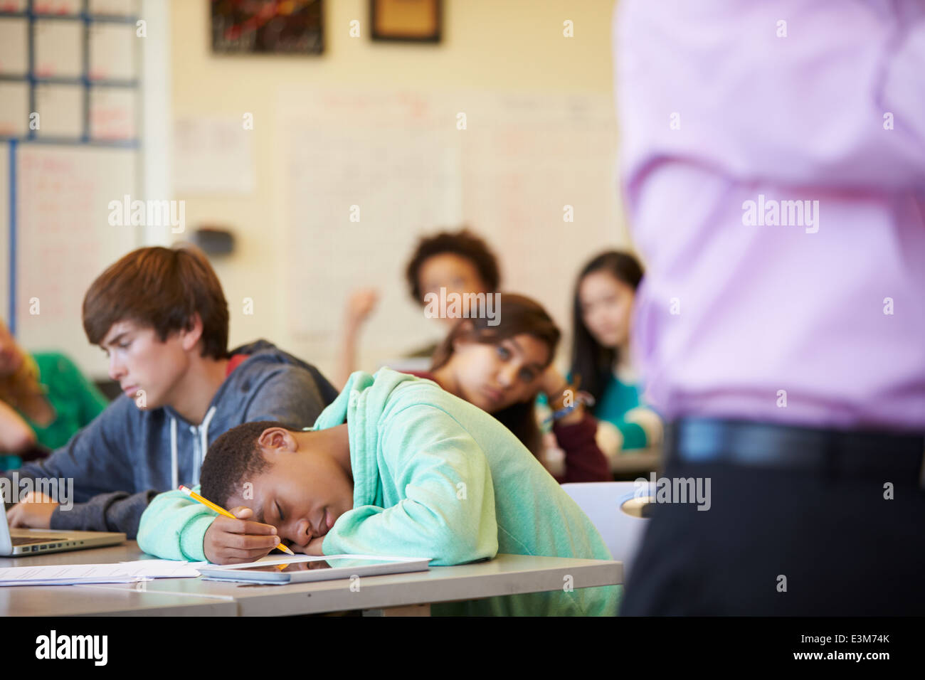 Gelangweilten Highschool-Schüler sank auf Schreibtisch im Klassenzimmer Stockfoto