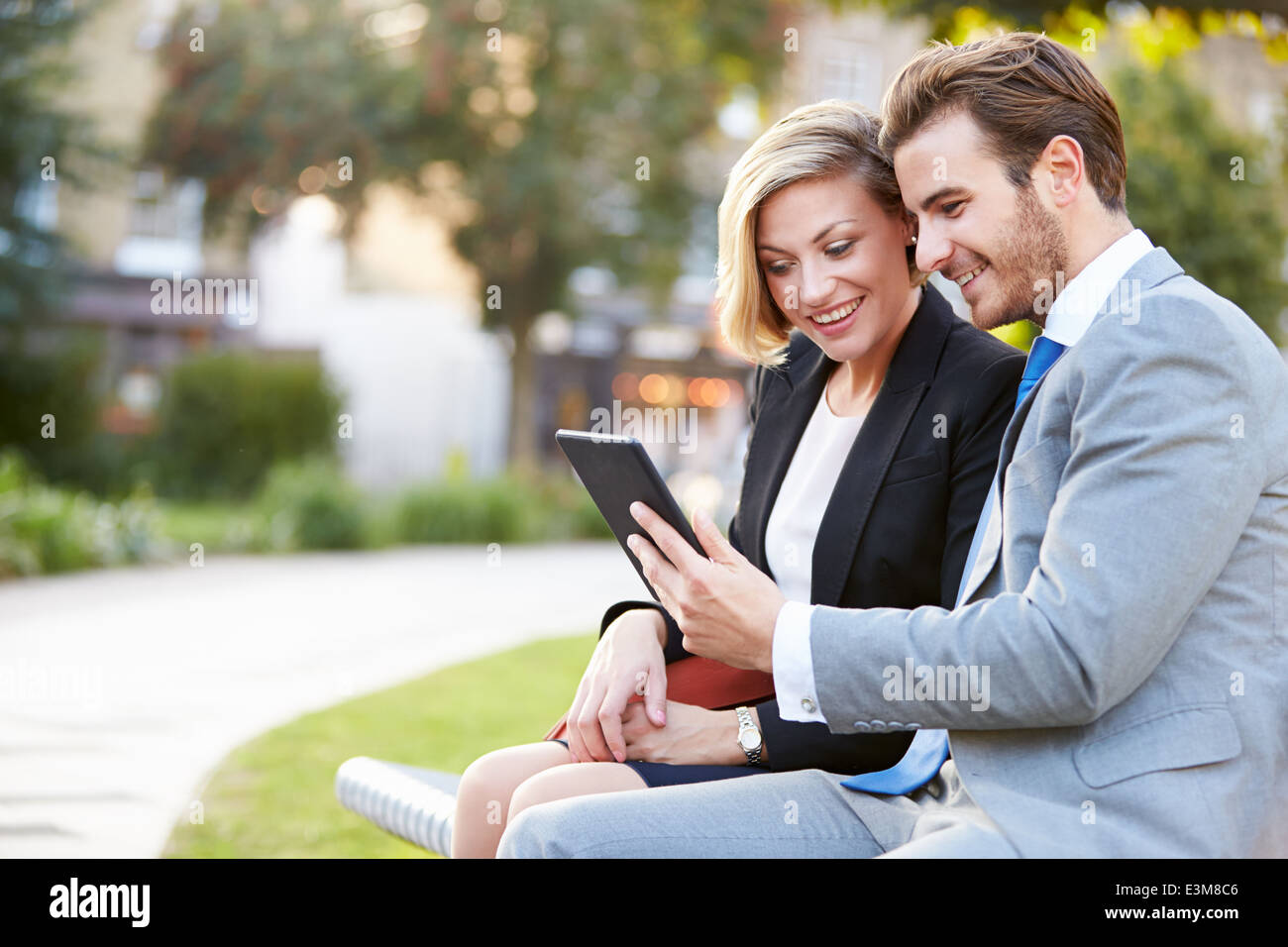 Business-paar mit Digital-Tablette auf Parkbank Stockfoto