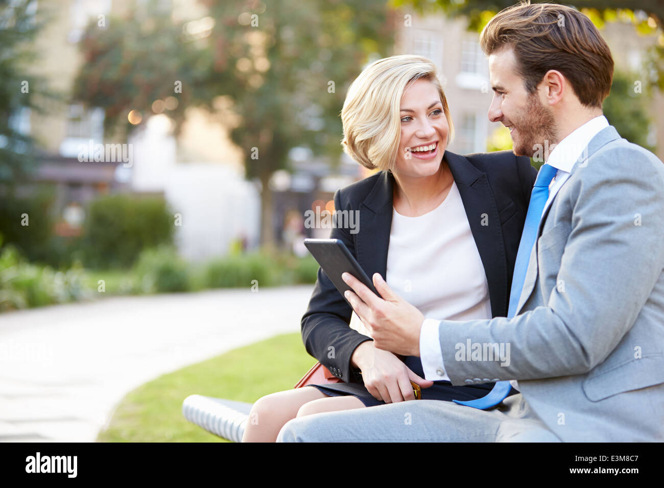 Business-paar mit Digital-Tablette auf Parkbank Stockfoto