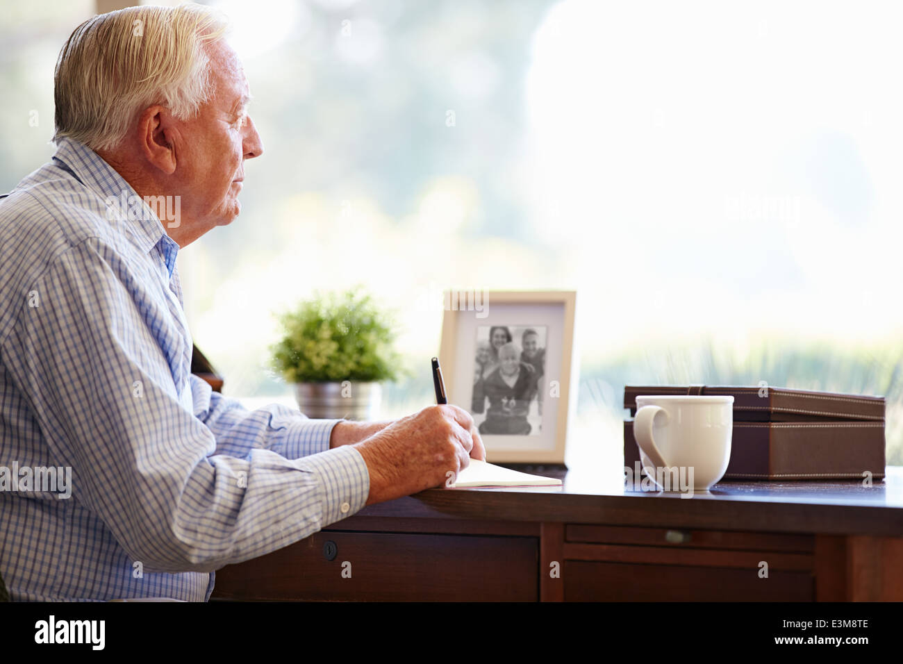 Senior woman schreiben Memoiren In Buch am Schreibtisch Stockfoto