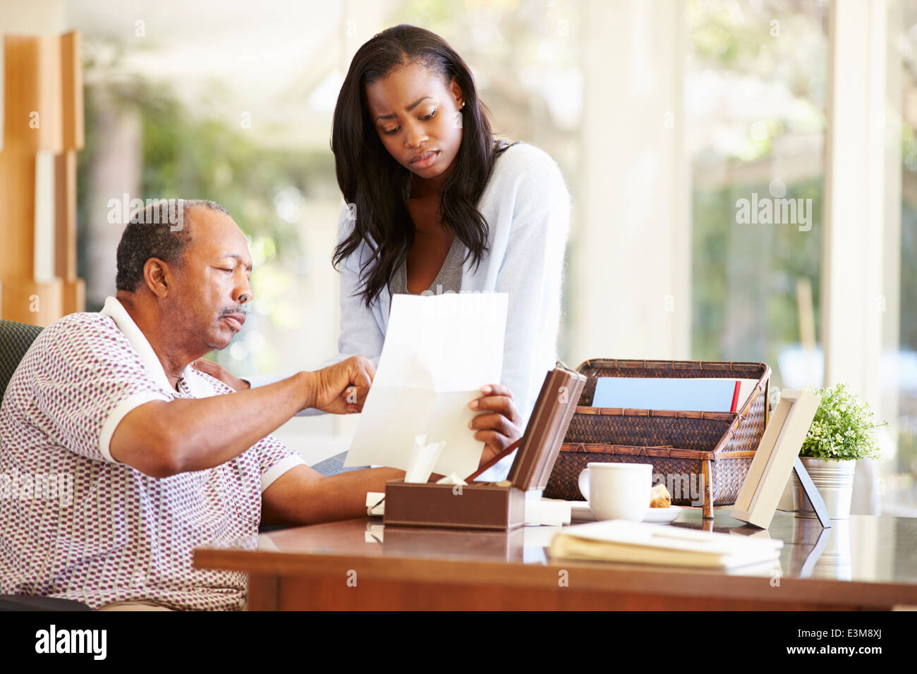 Senior-Vater diskutieren Dokument mit erwachsenen Tochter Stockfoto