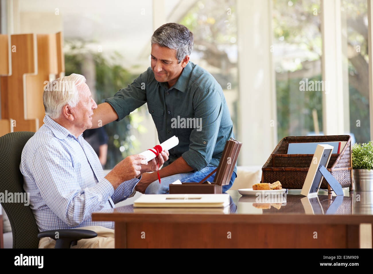 Senior-Vater diskutieren Dokument mit erwachsenen Sohn Stockfoto