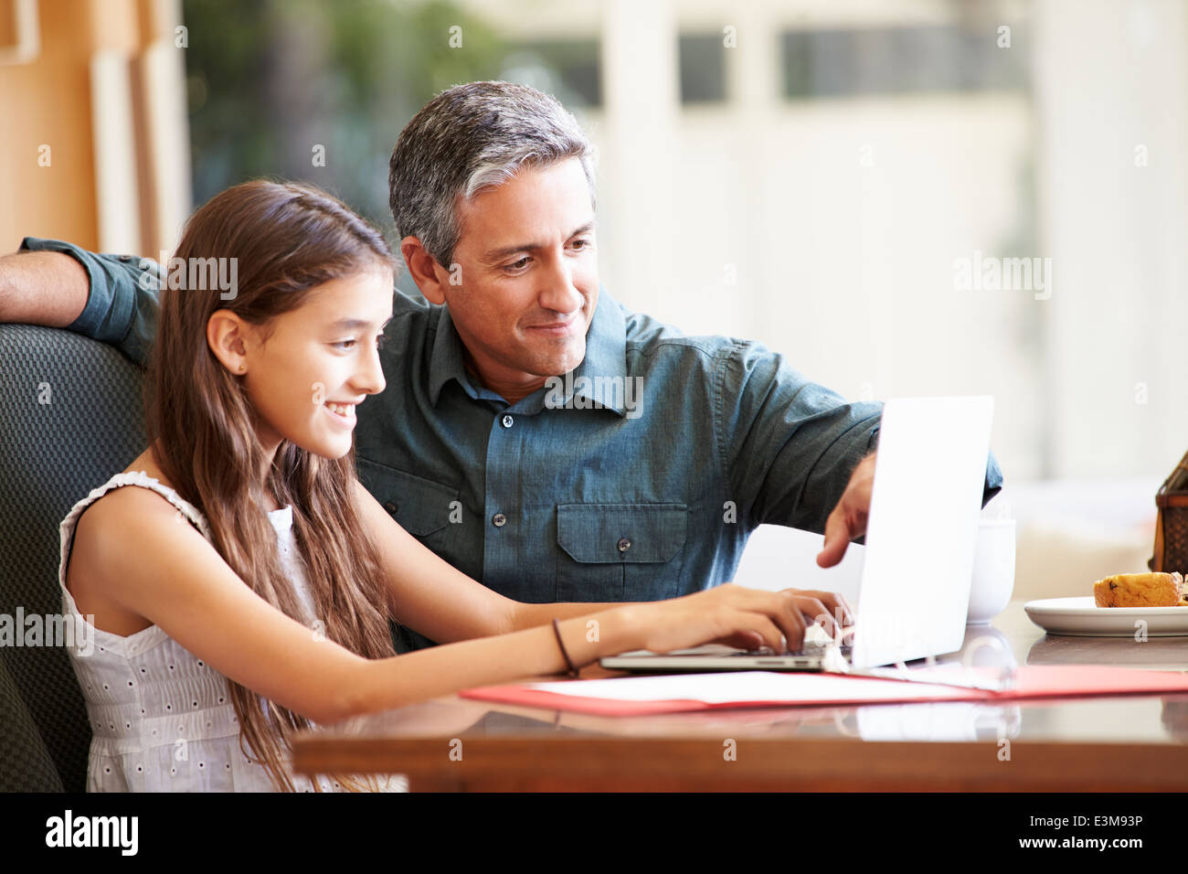 Vater und Tochter im Teenageralter Blick auf Laptop zusammen Stockfoto
