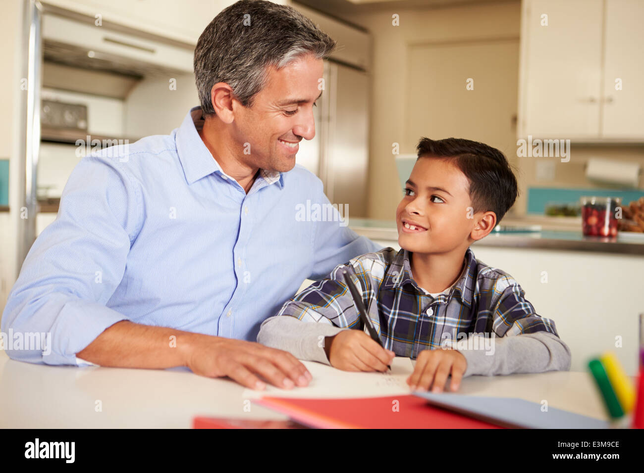 Hispanic Vater helfen Sohn bei den Hausaufgaben am Tisch Stockfoto