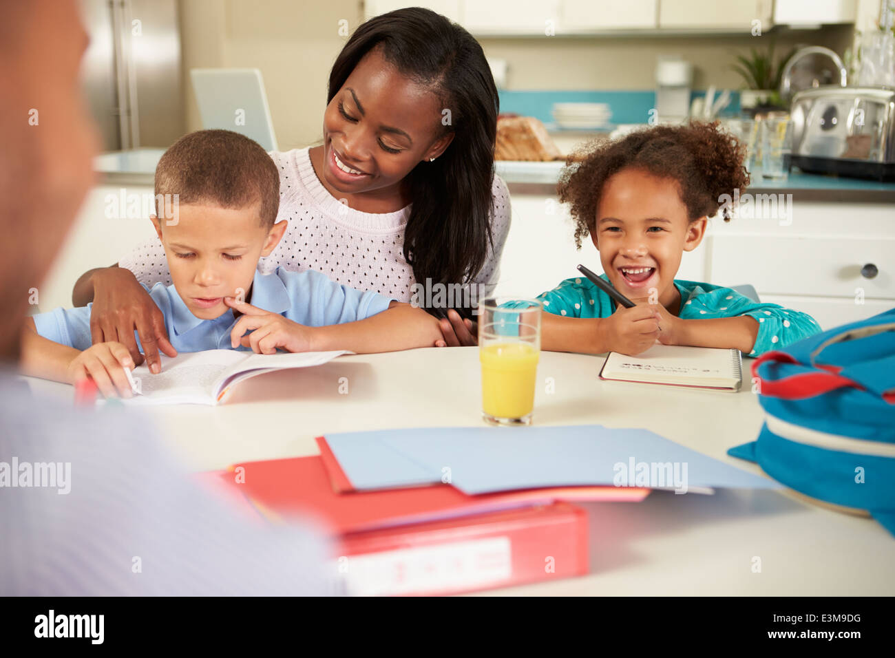 Mutter, Hilfe für Kinder bei den Hausaufgaben am Tisch Stockfoto