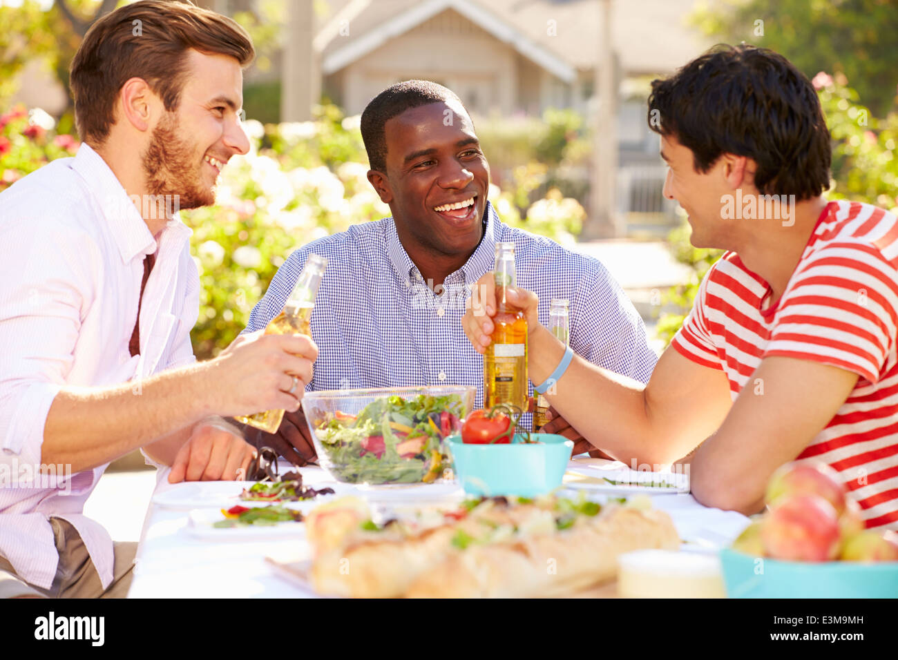 Drei männliche Freunde genießen Mahlzeit auf Outdoor-Party Stockfoto