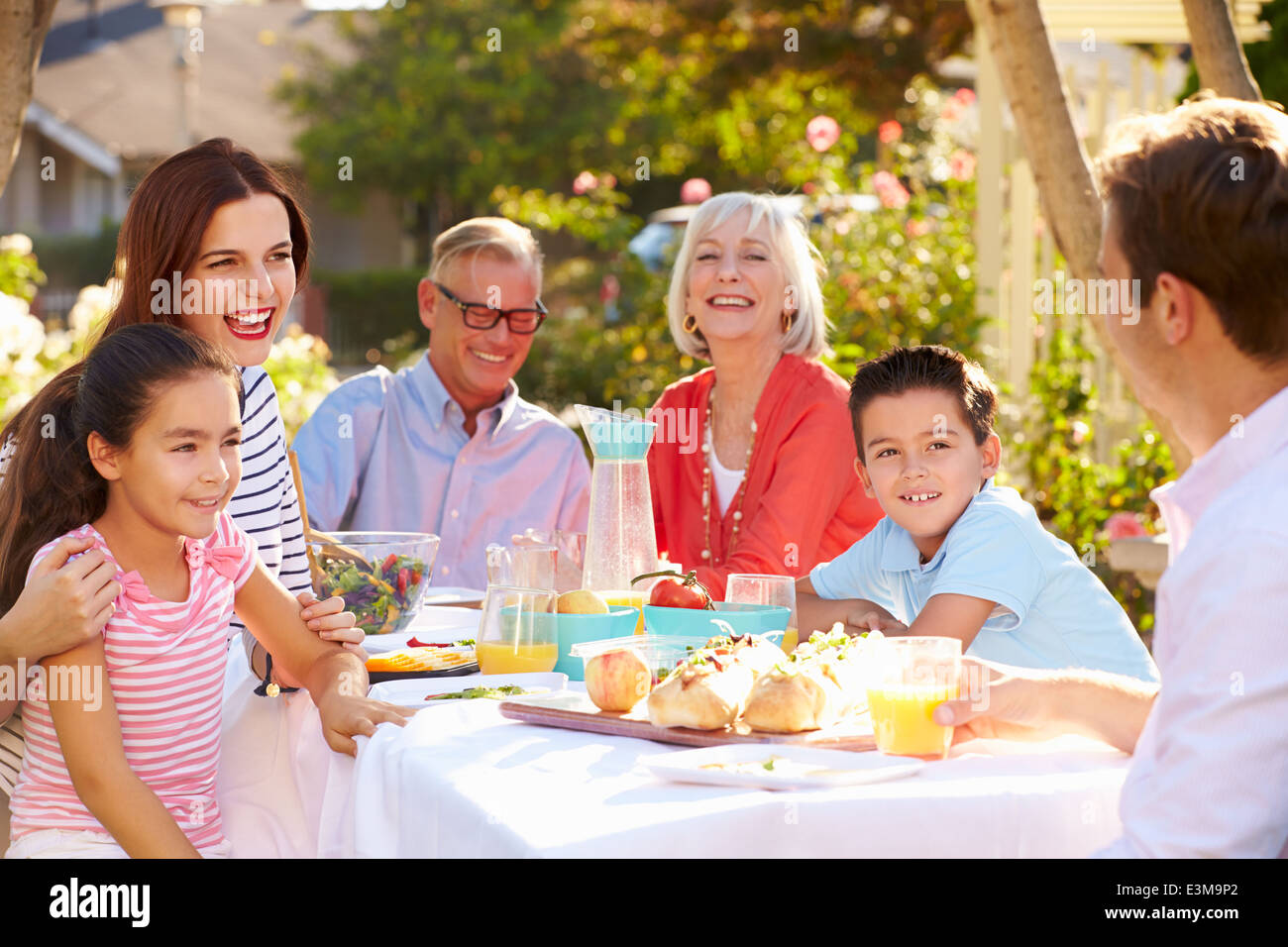 Mehr-Generationen-Familie Mahlzeit im Freien im Garten genießen Stockfoto