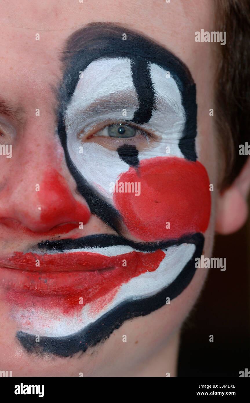 Teenager mit Hälfte seines Gesichts gemalt als Clown. Stockfoto