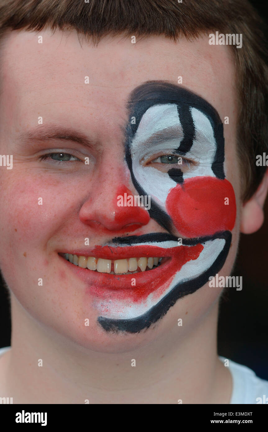 Teenager mit Hälfte seines Gesichts gemalt als Clown. Stockfoto