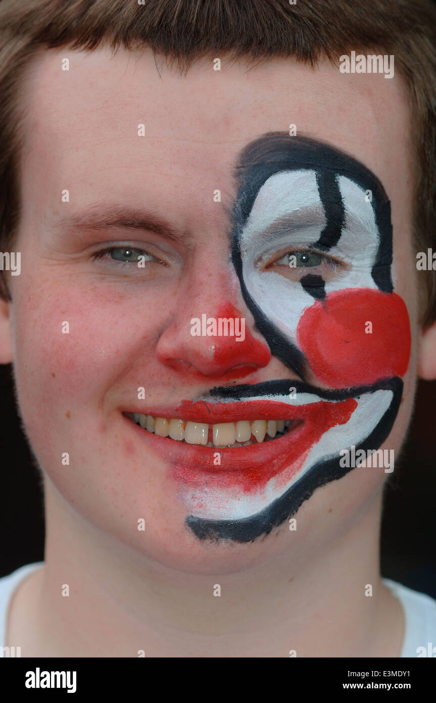 Teenager mit Hälfte seines Gesichts gemalt als Clown. Stockfoto