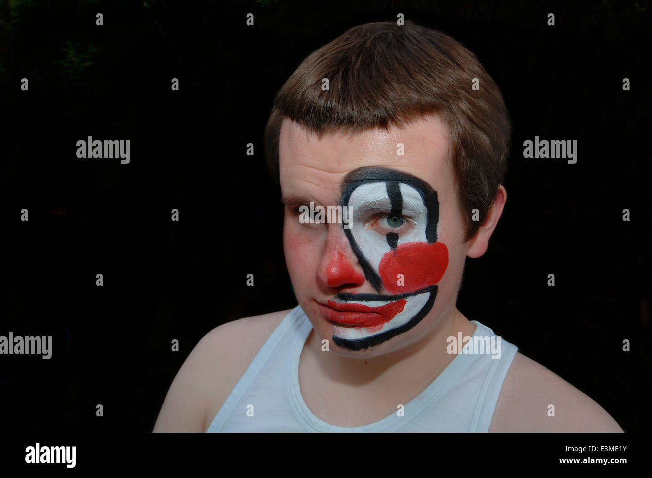 Teenager mit Hälfte seines Gesichts gemalt als Clown. Stockfoto