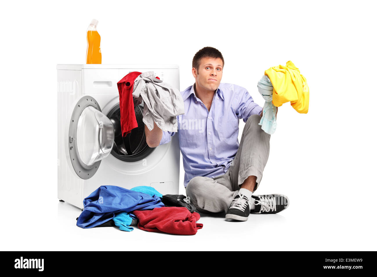 Verwirrt junger Mann sitzt eine Waschmaschine Wäsche Stockfoto