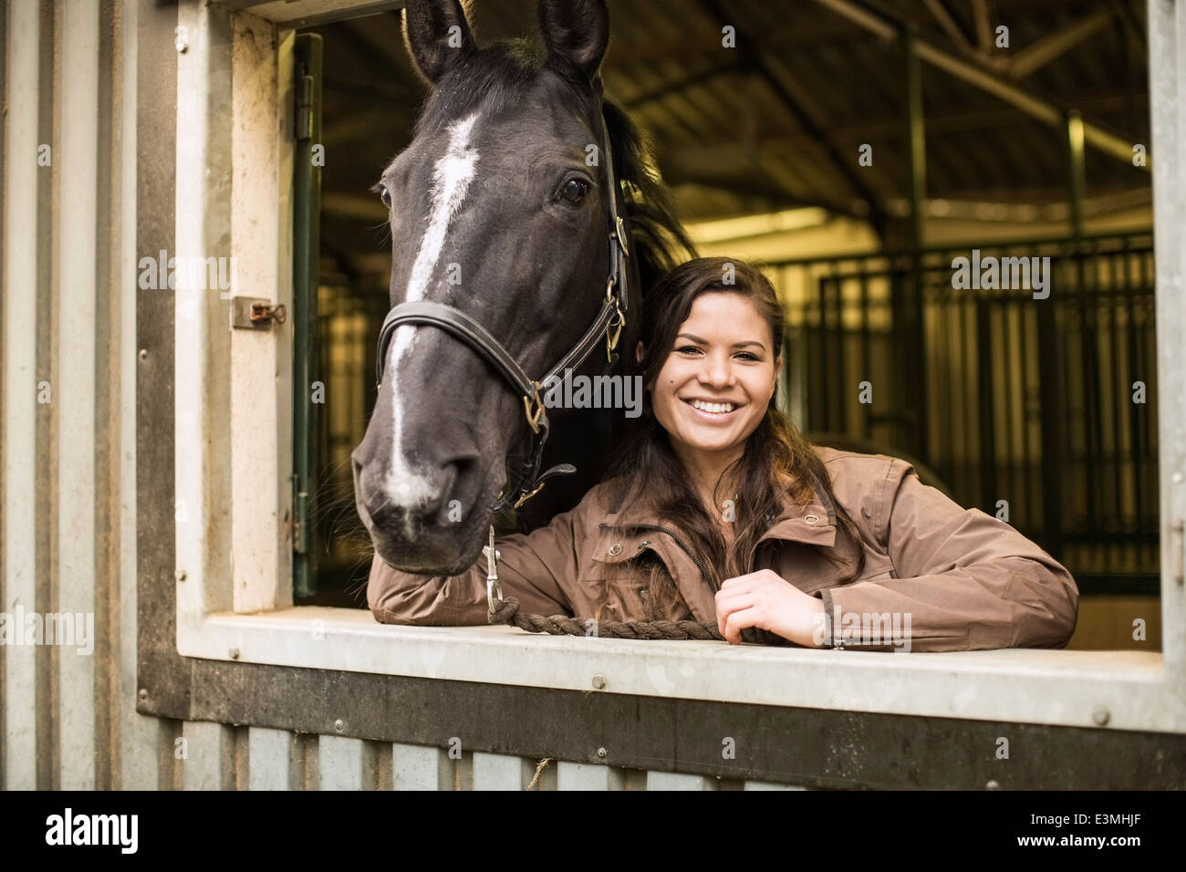 Porträt der glückliche junge Frau mit Pferd im Stall Stockfoto