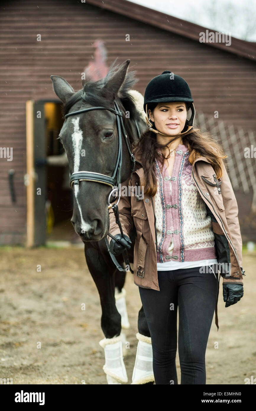 Junge Frau mit Pferd zu Fuß außerhalb Scheune Stockfoto