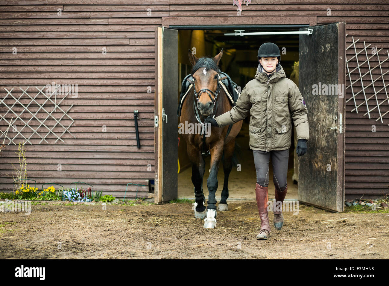 Gesamte Länge der Jüngling mit Pferd Stall verlassen Stockfoto