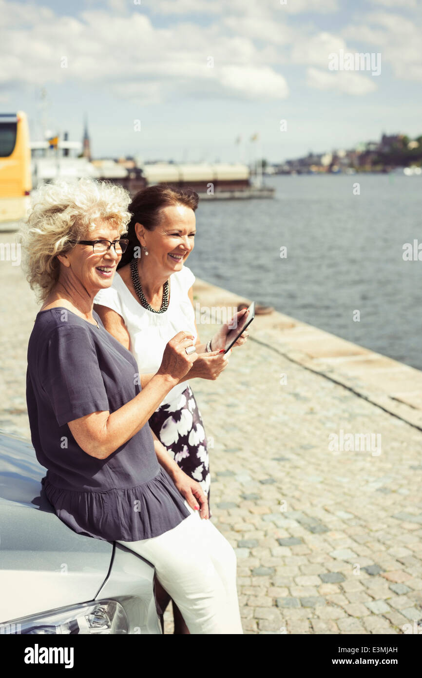 Glückliche Frauen in Führungspositionen stützte sich auf Auto am Flussufer Stockfoto