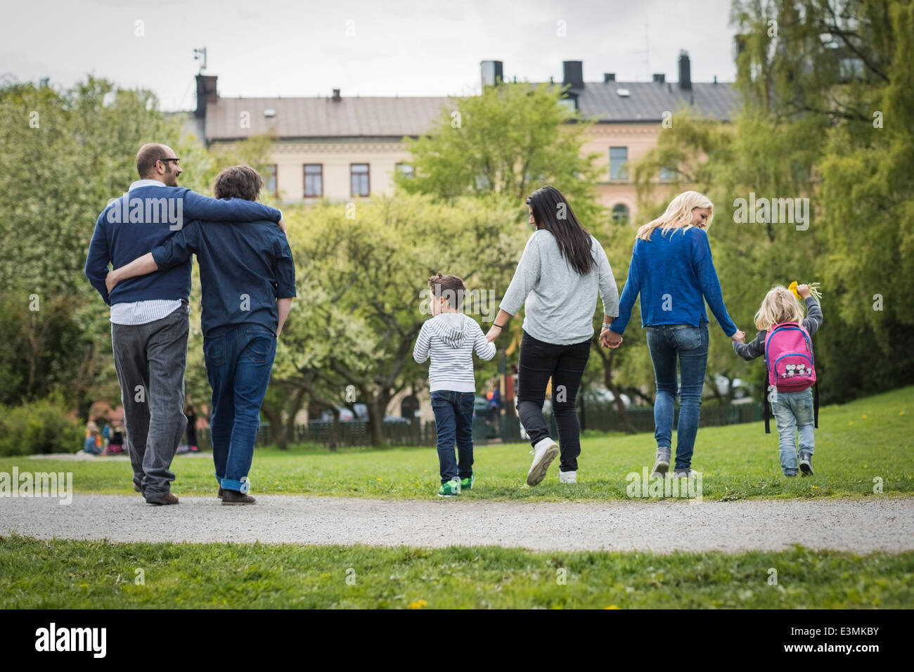 Rückansicht des weiblichen Homosexuellen Familie gehen im Park mit schwules Paar im Hintergrund Stockfoto