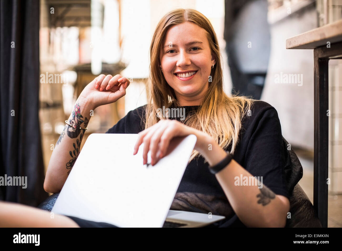 Porträt der glückliche junge Geschäftsfrau mit Laptop sitzen auf Sitzsack in kleinen Büros Stockfoto