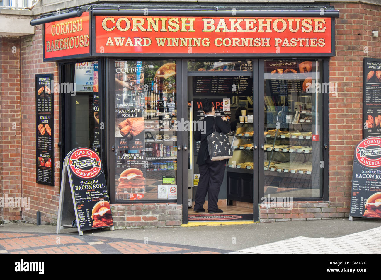 Vorne ein Einzelhandelsgeschäft Cornish Backhaus & Bäckerei in Swindon, Wiltshire, UK mit einem Kunden dienend Stockfoto