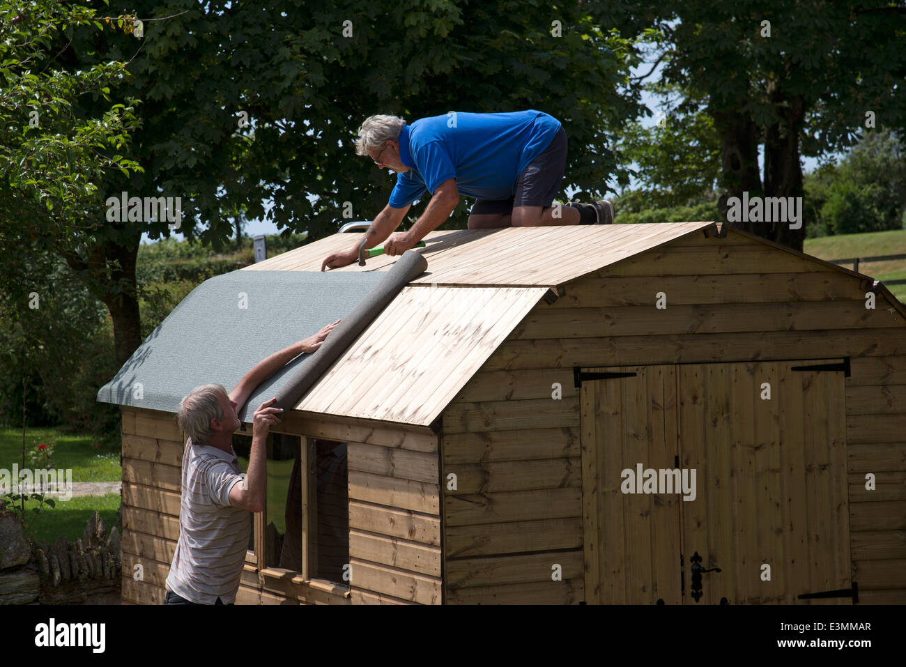 Errichtung eines neuen hölzerne Gartens Schuppen Applying Dachpappe Stockfoto