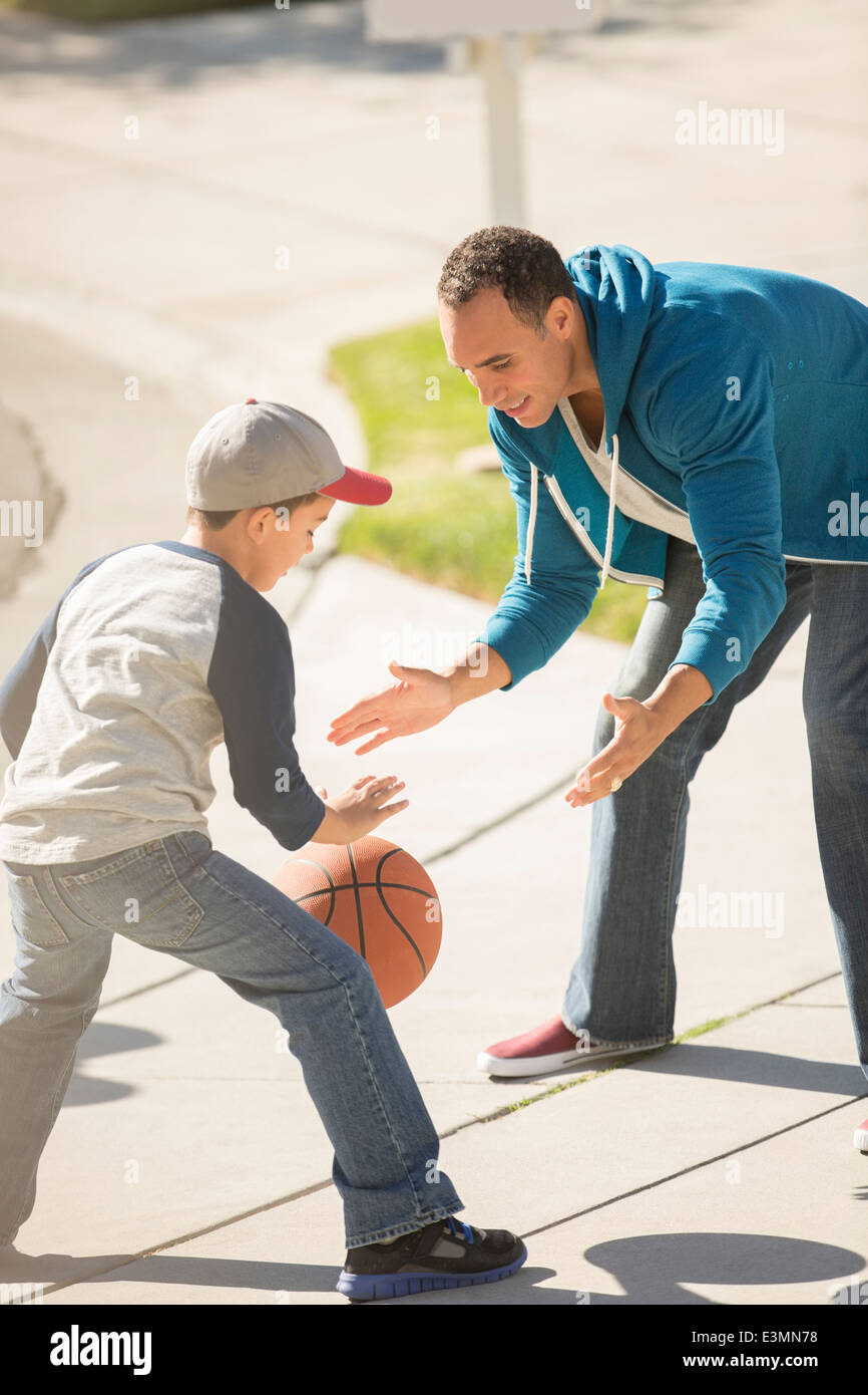 Vater und Sohn spielen Basketball in sonnigen Einfahrt Stockfoto
