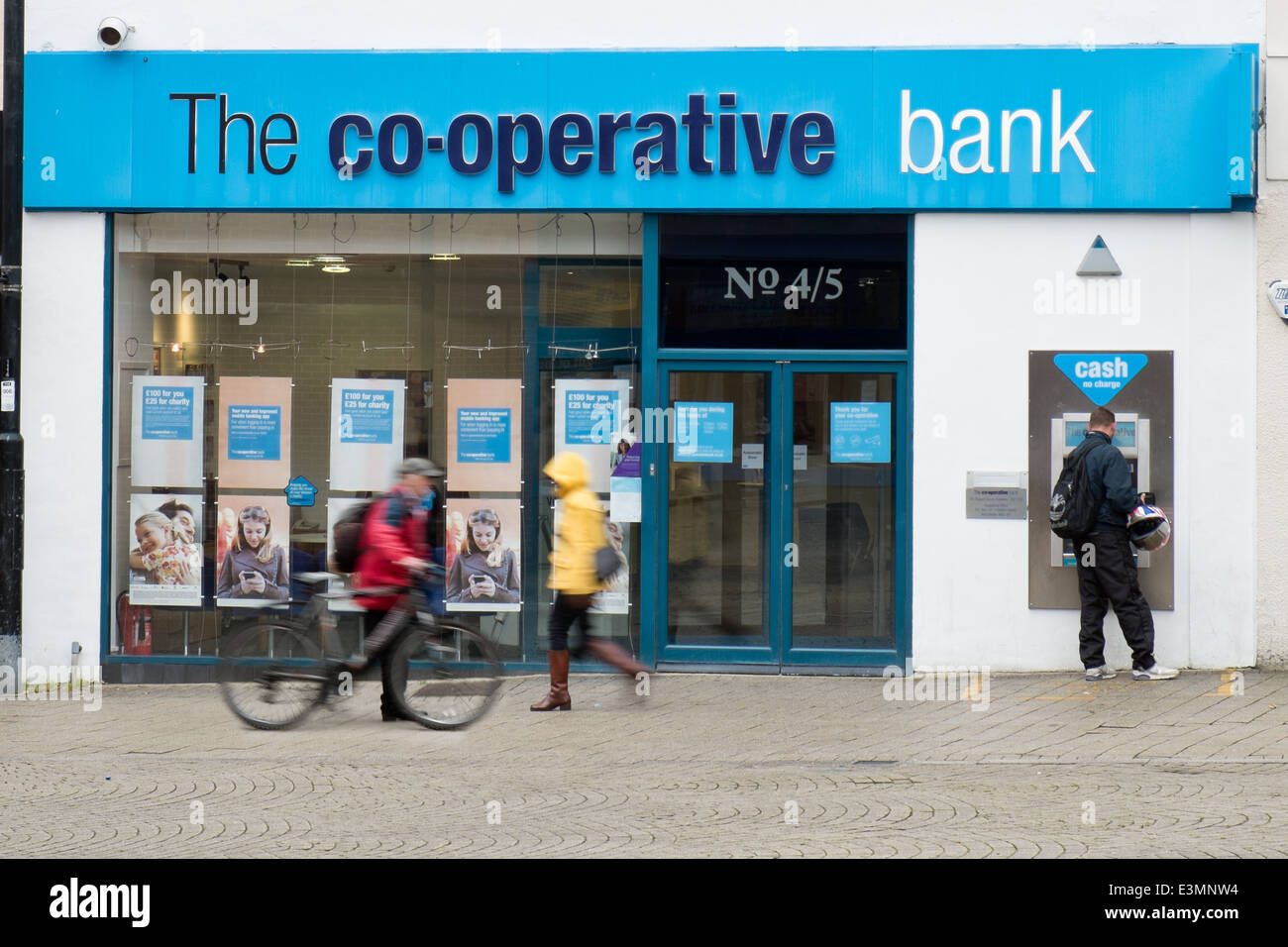 Ein Mann mit Cashpoint & Bewegung verwischt Passanten vorbei an Swindon Verzweigung der Co-Operative Bank Stockfoto