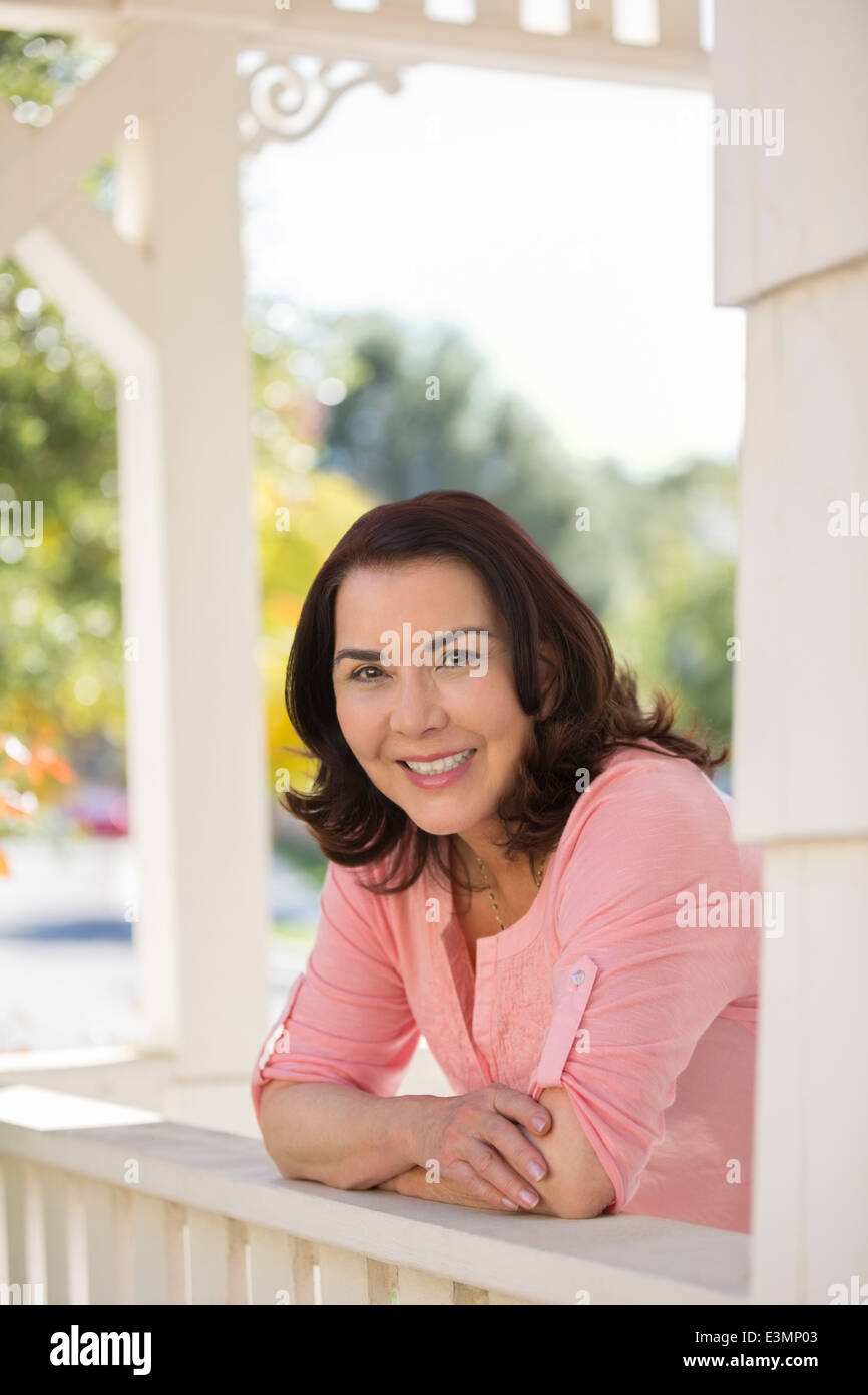 Porträt der lächelnde Frau stützte sich auf Veranda Geländer Stockfoto