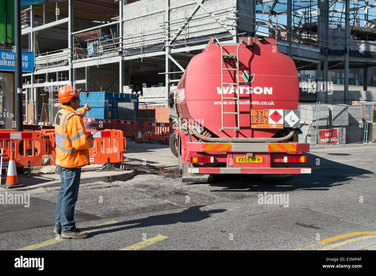 Ein Banksman auf einer britischen Baustelle tragen persönlicher Schutzausrüstung sicher Regie ein Tankwagen Lieferung Stockfoto