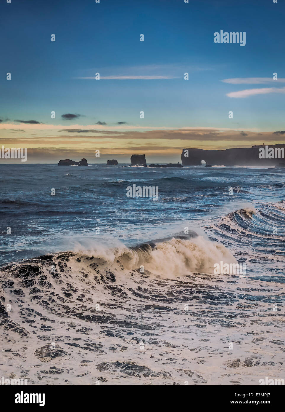 Wellen am Ufer mit Dryholaey im Hintergrund, Island. Dyrhólaey übersetzt bedeutet "die Tür Loch-Insel" Stockfoto