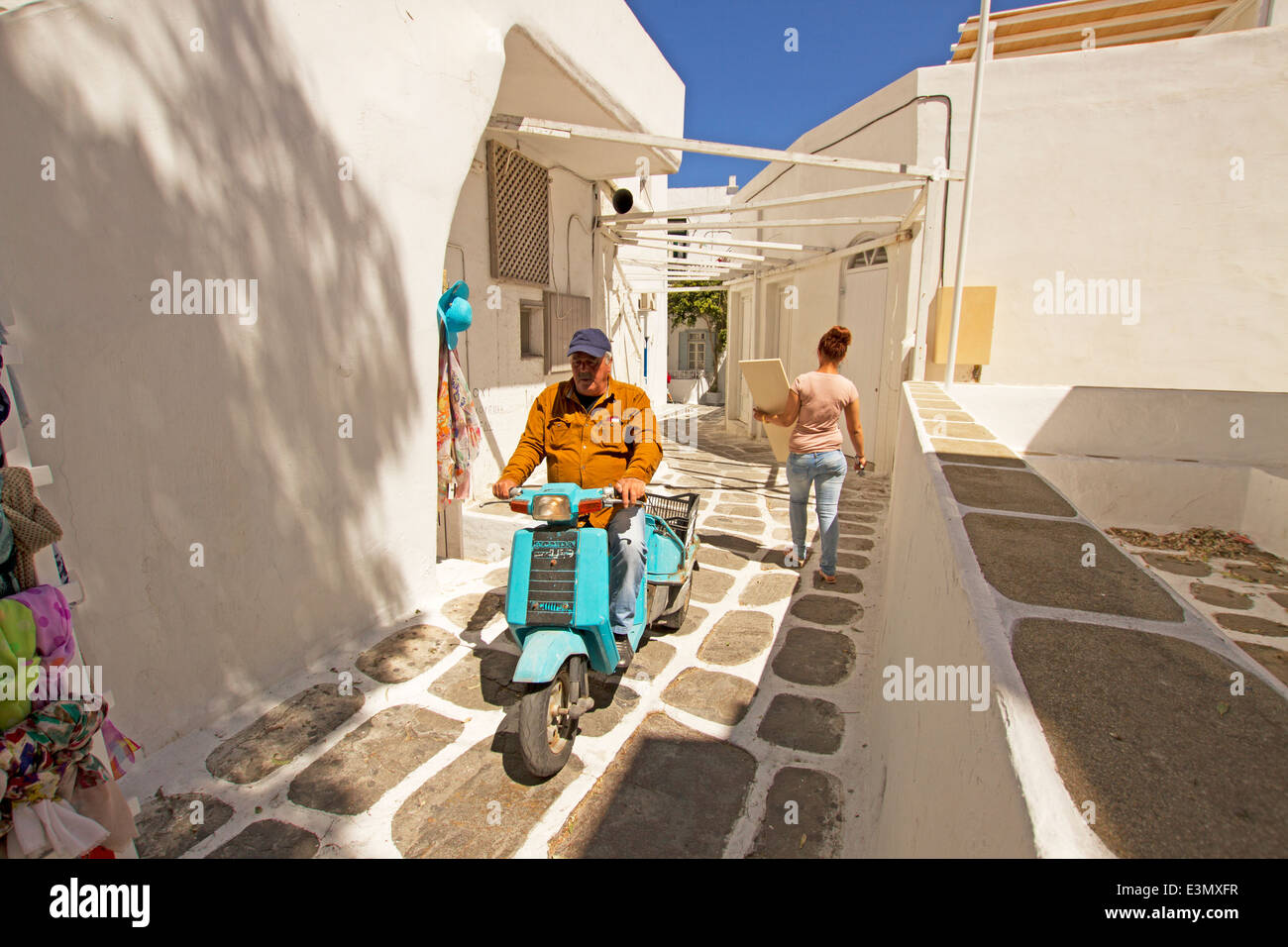 Lokale Mann Scooter in Steinstraße Gasse, Mykonos-Stadt, Griechenland zu befreien. Stockfoto