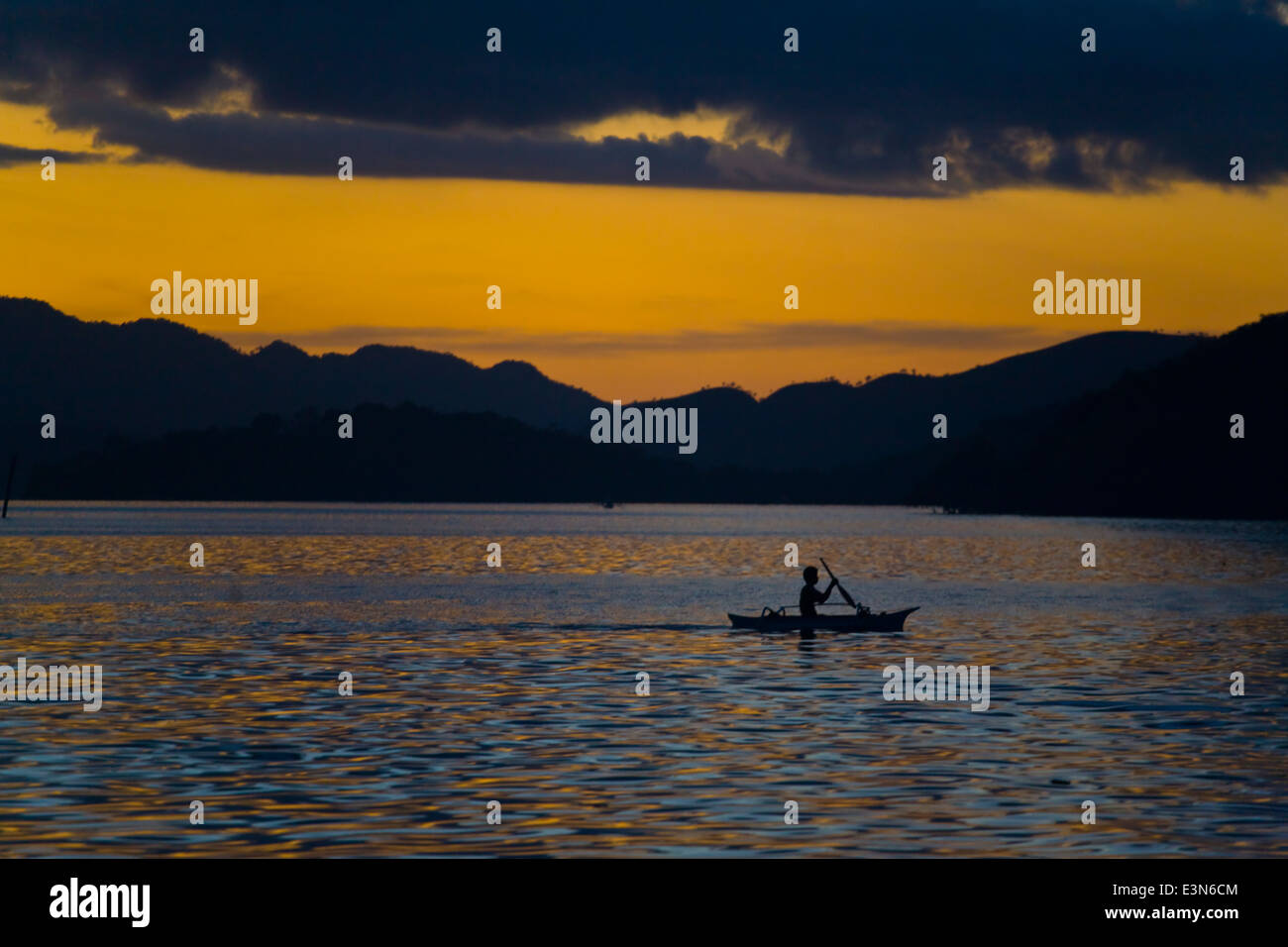 Sonnenuntergang hinter einem kleinen Ruderboot in der Nähe von BUSUANGA ISLAND in der CALAMIAN Gruppe - Philippinen Stockfoto