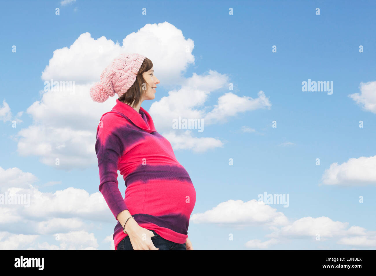 Seitenansicht der schwangeren Frau stehend gegen bewölktem Himmel Stockfoto
