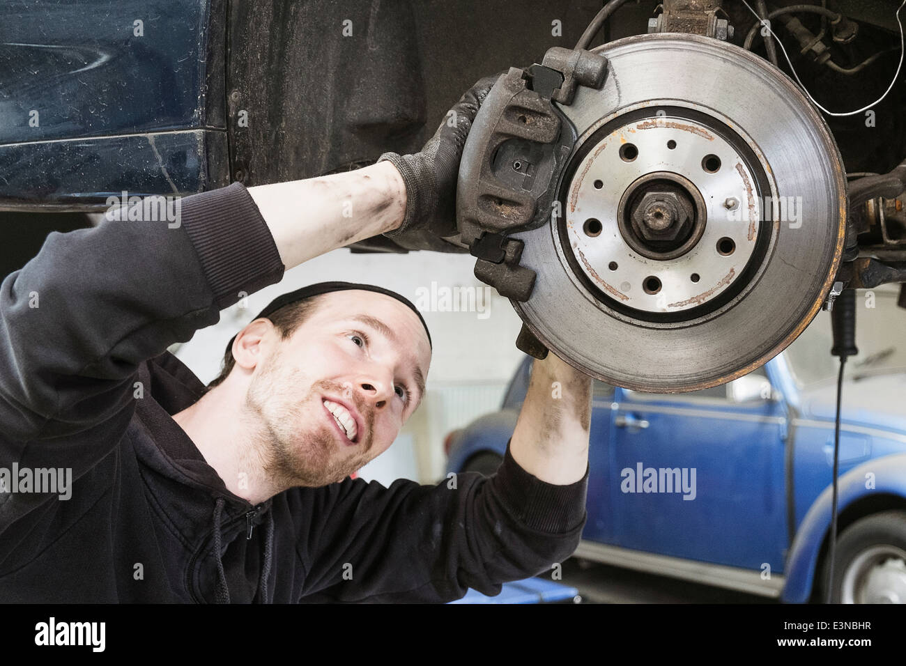Lächelnd männlichen Arbeitnehmer Reparatur Autos in Auto-Werkstatt Stockfoto