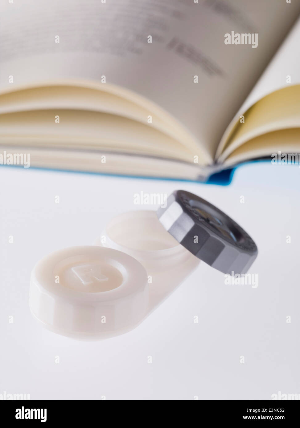 Nahaufnahme von Kontaktlinsen Fall und Buch auf weißem Hintergrund Stockfoto