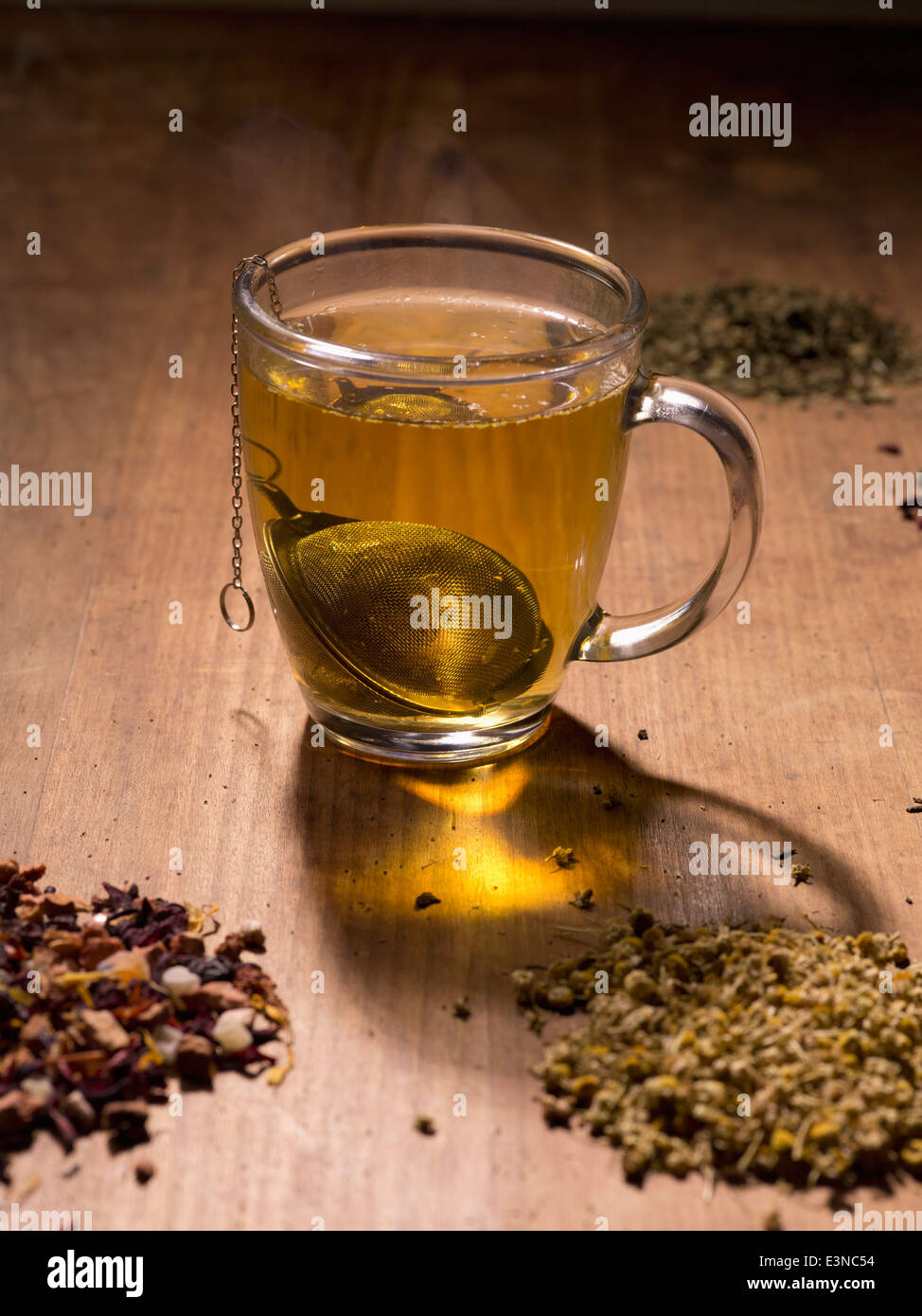 Teesieb in Tasse mit Kräutern auf Tisch Stockfoto