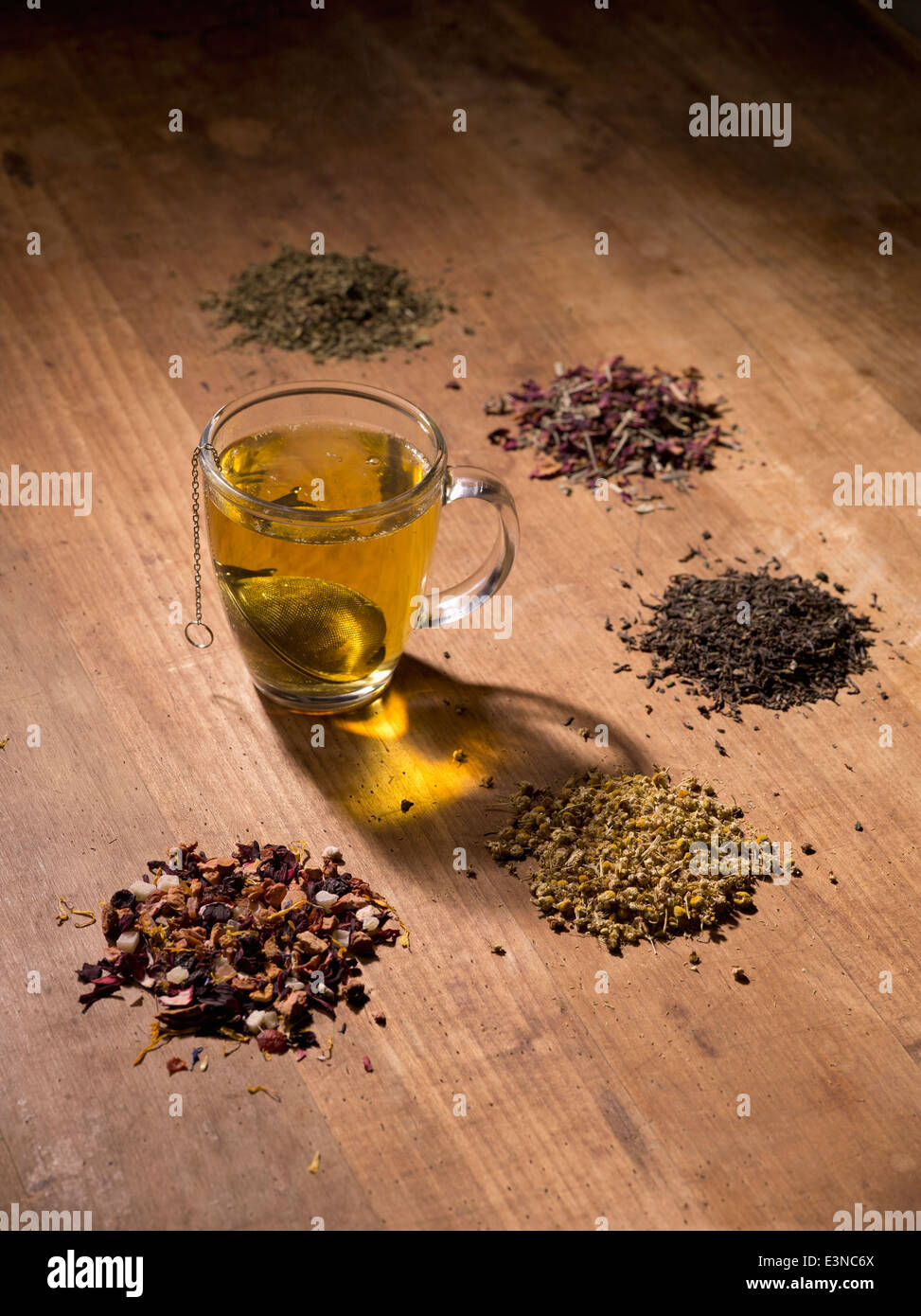 Teesieb in Tasse mit Kräutern auf Holztisch Stockfoto
