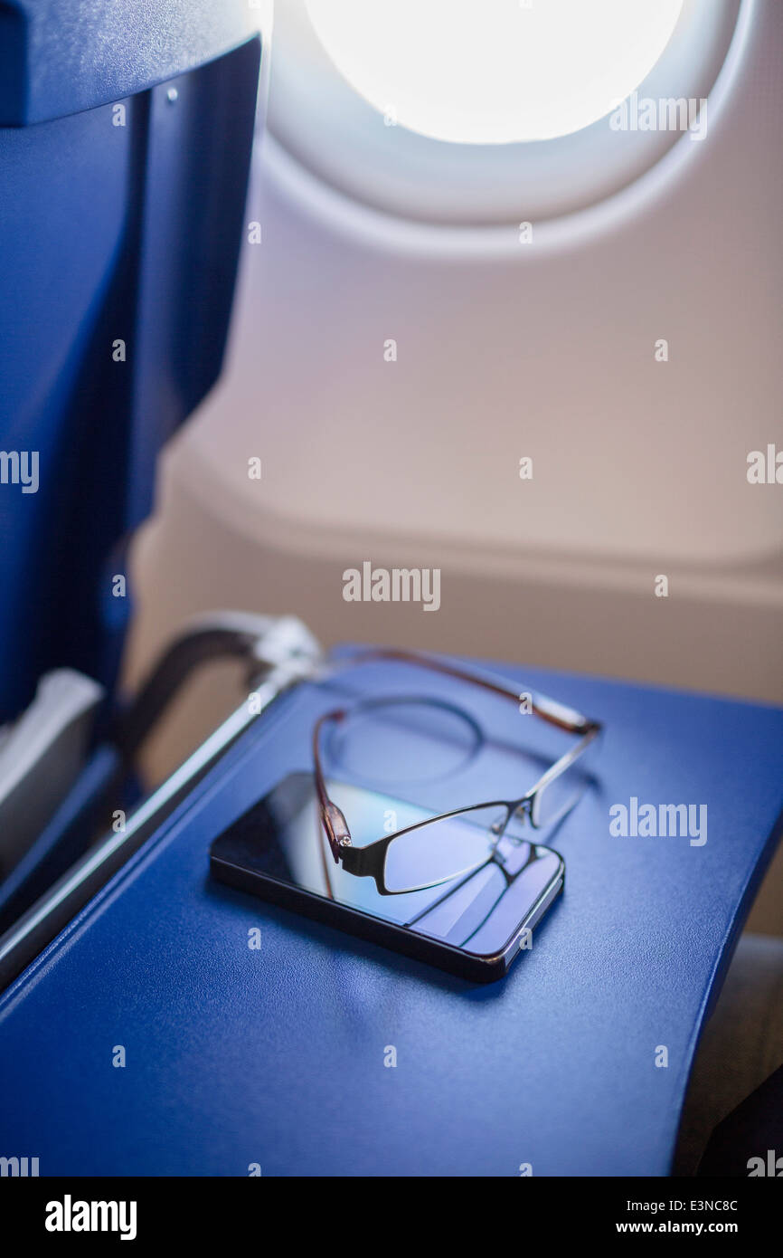 Smartphone und Gläser auf Tisch im Flugzeug Stockfoto