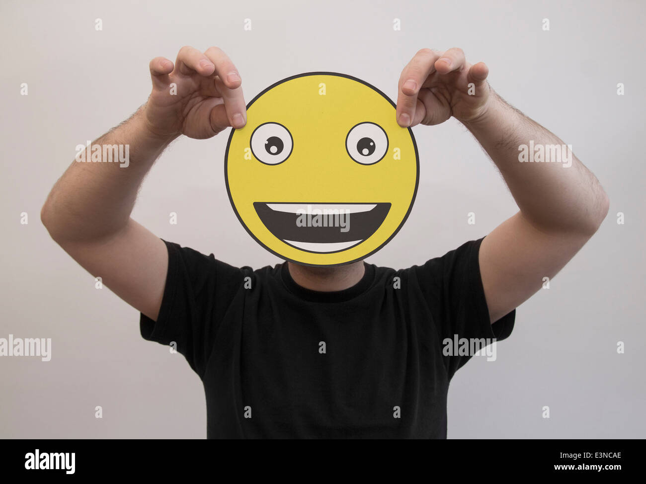 Mann, der ein wirklich glücklich Emoticon Gesicht vor sein Gesicht hält Stockfoto