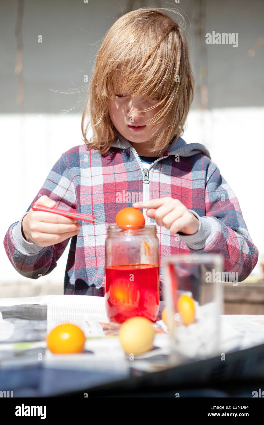 Junge, Ostereier färben, indem man sie in Gläser mit Farbe Stockfoto
