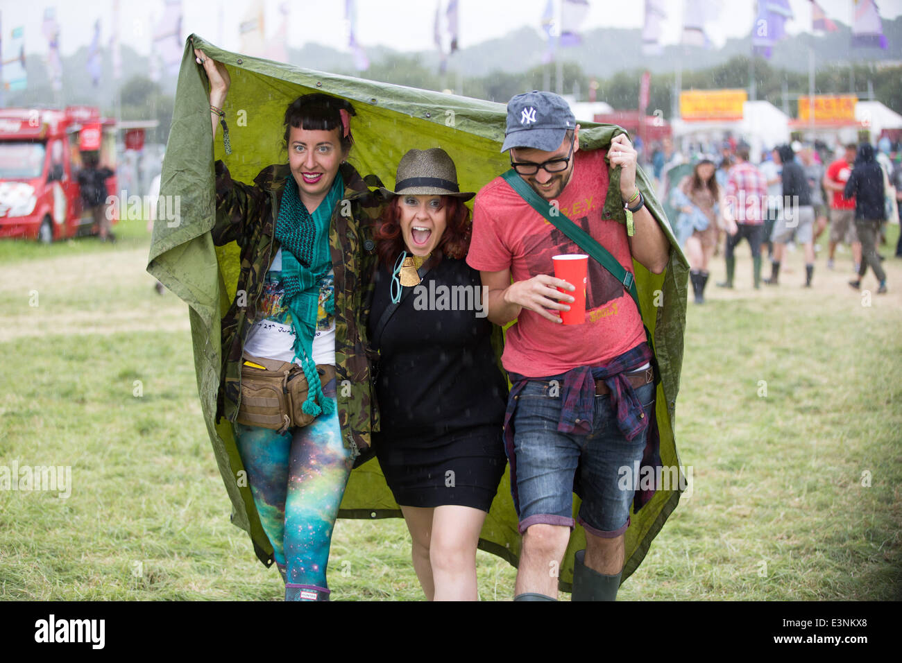 Glastonbury, Somerset, UK. 26. Juni 2014. Festivalbesucher vertuschen vor dem Regen auf dem 2014 Glastonbury Festival würdig Farm in Somerset. Europas größte Festival beginnt morgen offiziell. 26. Juni 2014. Bildnachweis: Lloyd/Alamy Live-Nachrichten Stockfoto