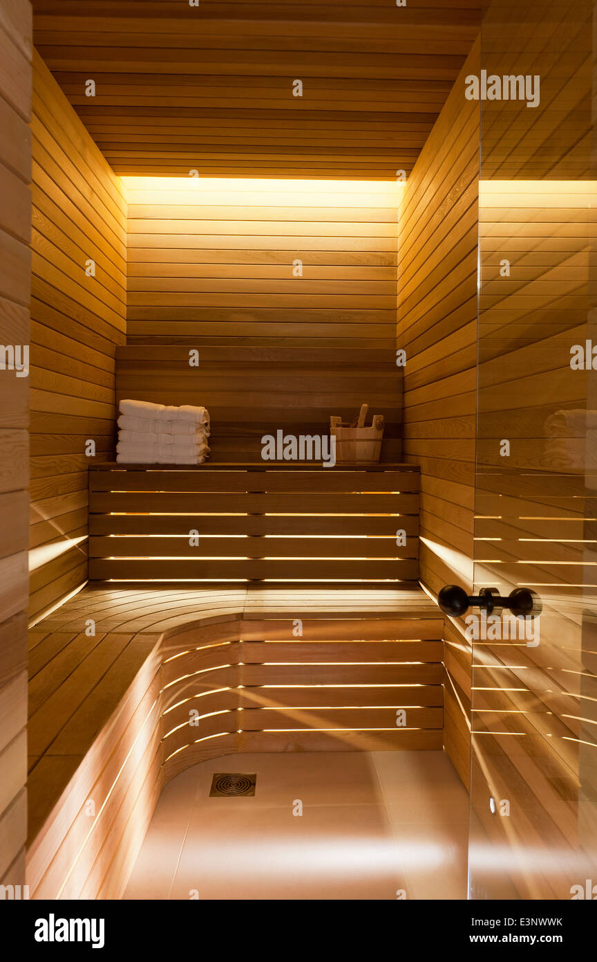 Holz getäfelten Wänden und Sitzgelegenheiten in Sauna mit Glastür Stockfoto