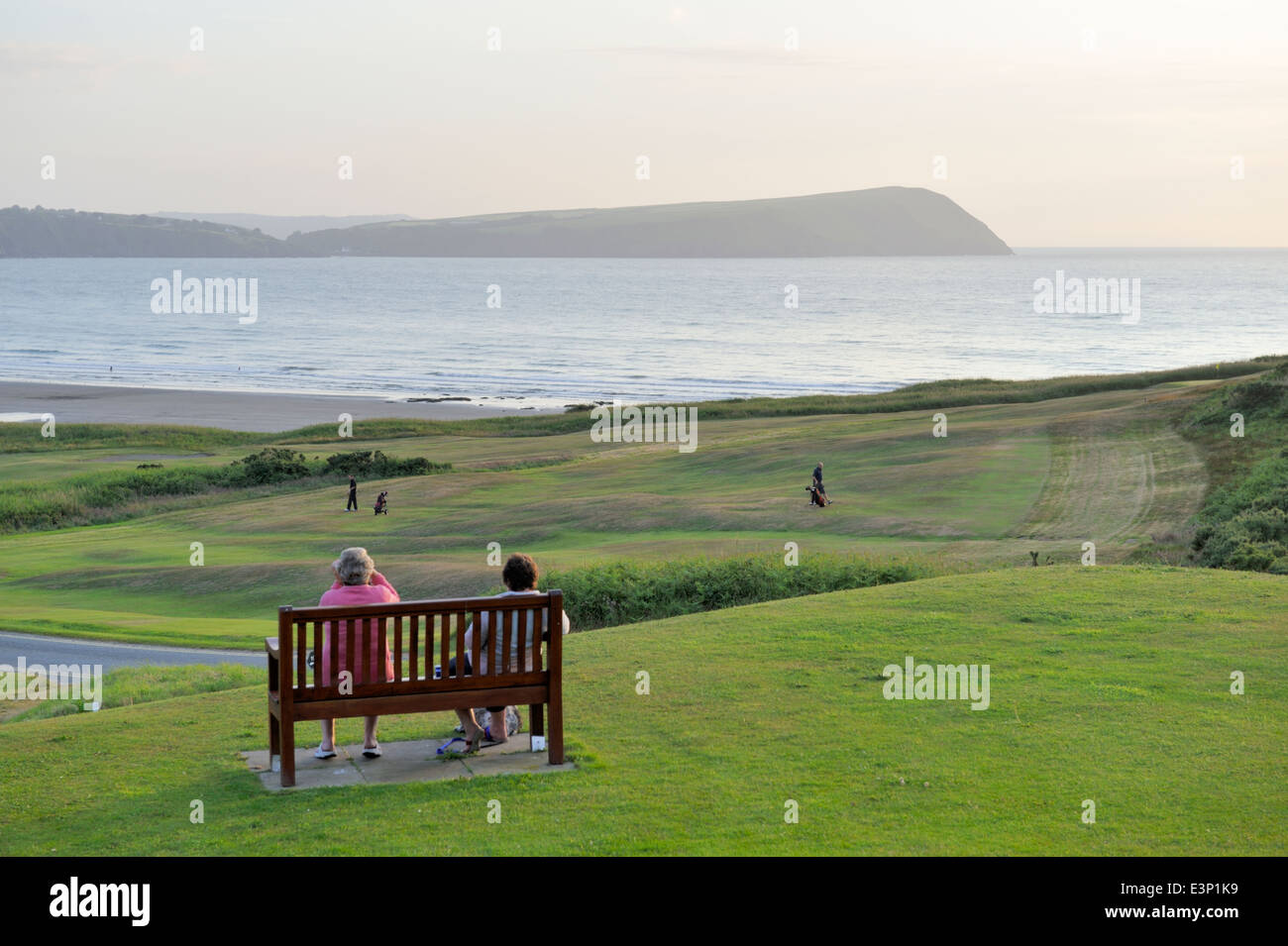 Newport Links Golf Club, Frau auf der Bank mit Blick auf Strand von Newport, Pembrokeshire, Wales, UK Stockfoto