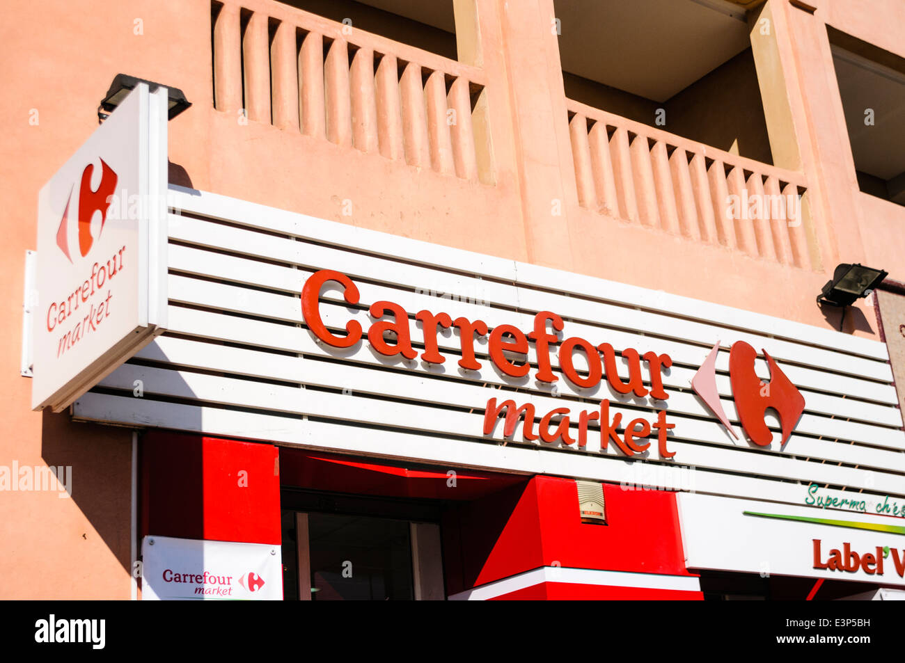 Rote und weiße Schilder mit Logo vor dem Eingang zu einem Carrefour Shop, eine berühmte französische Supermarktkette. Stockfoto