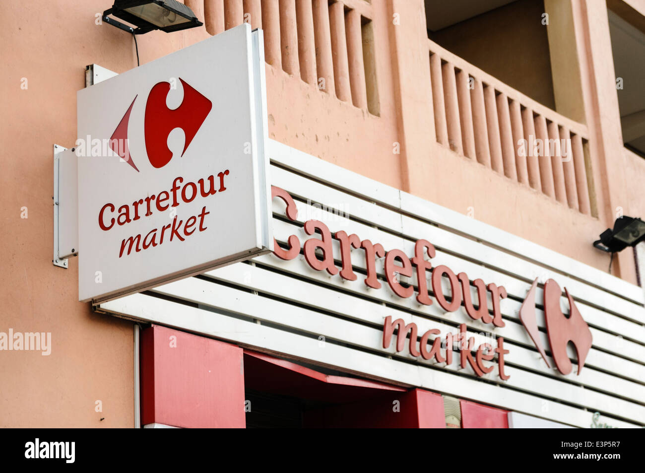 Rote und weiße Schilder mit Logo vor dem Eingang zu einem Carrefour Shop, eine berühmte französische Supermarktkette. Stockfoto