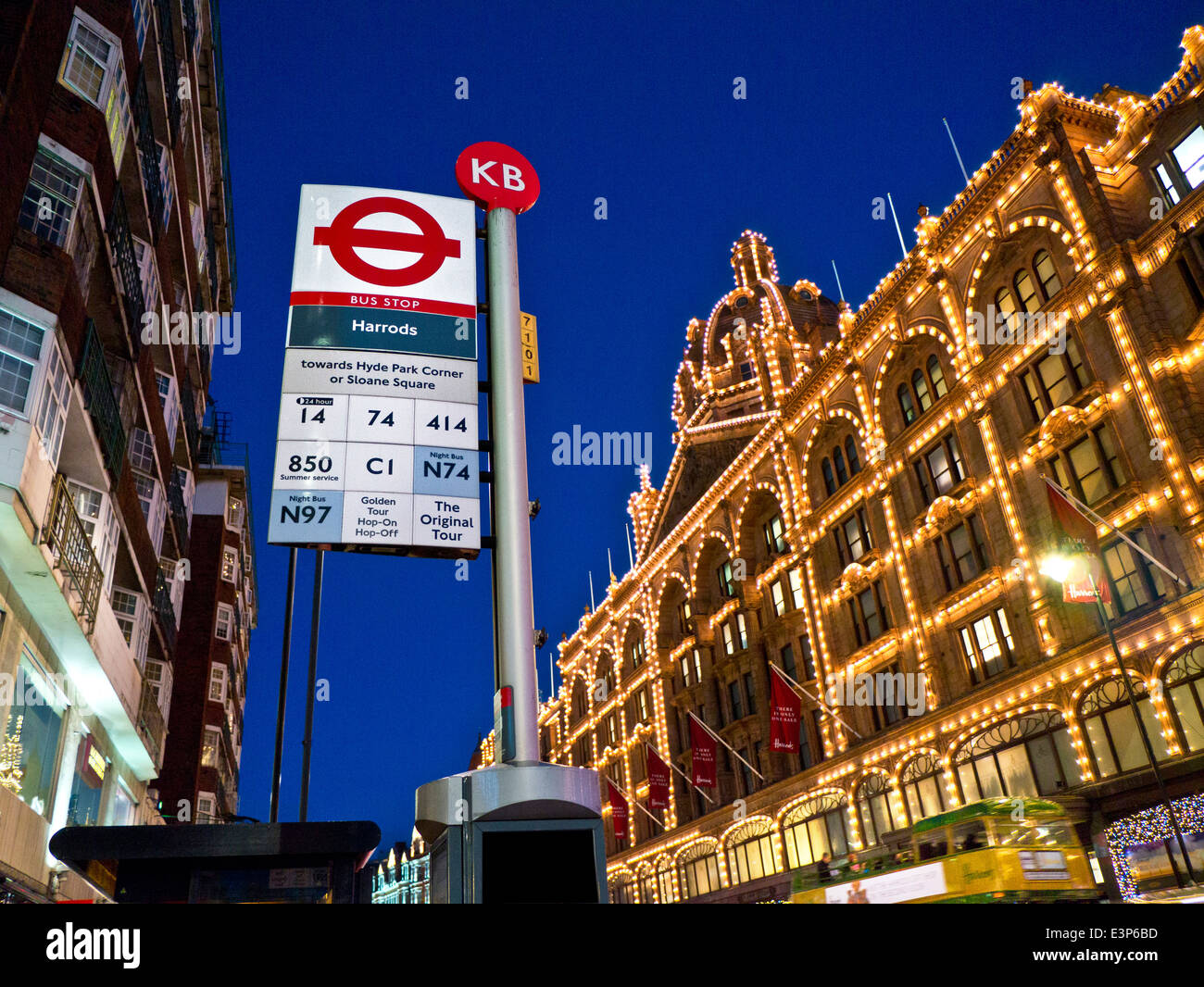 Bushaltestelle Harrods Kaufhaus bei Nacht mit eigener Bushaltestelle und am Harrods Tourbus vorbei in b/g Knightsbridge London UK Stockfoto