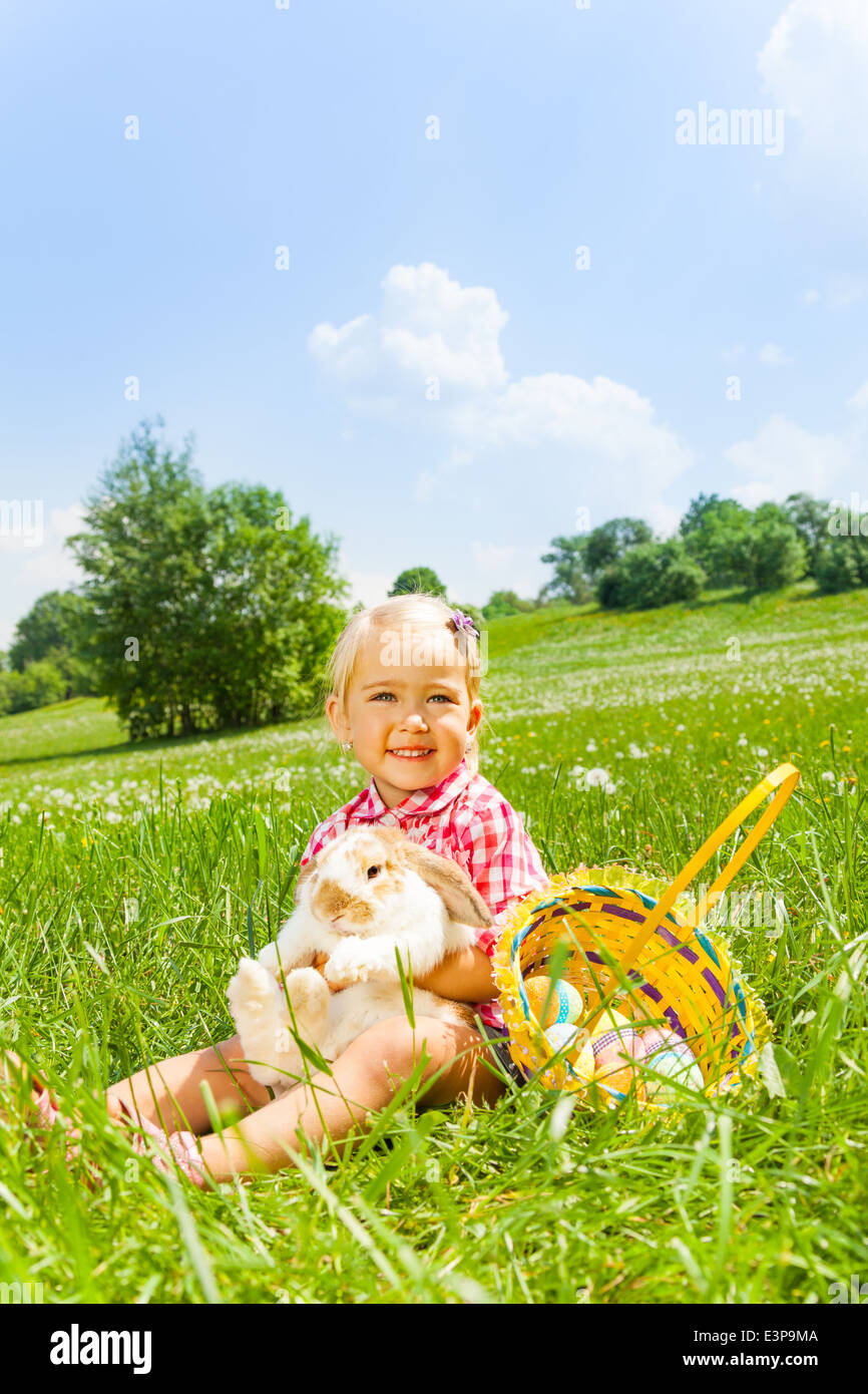 Glückliches kleines Mädchen kuschelt Kaninchen auf grüner Wiese Stockfoto