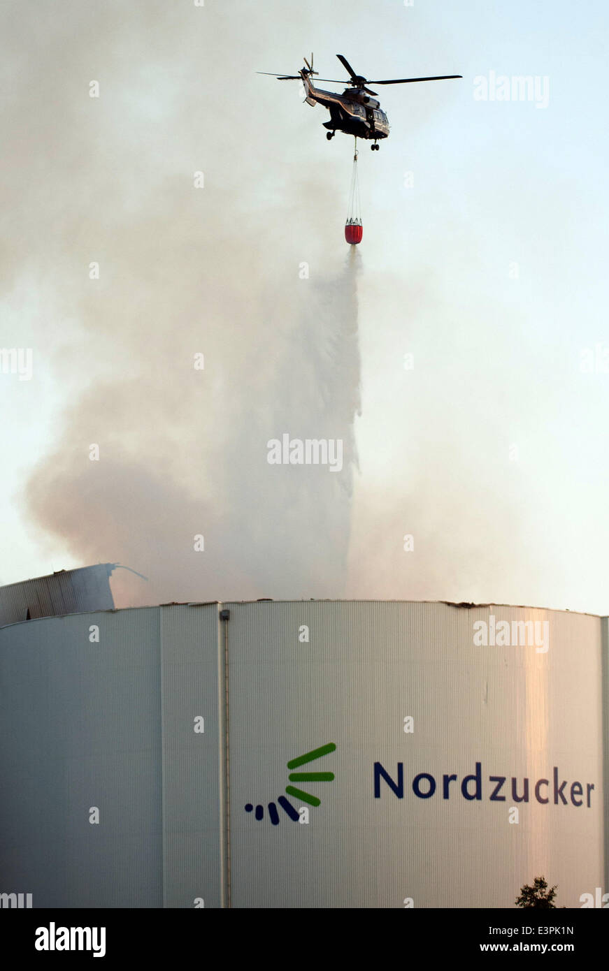 Uelzen, Deutschland. 26. Juni 2014. Ein Polizeihubschrauber gießt Wasser auf einem brennenden Silo bei Nordzucker AG in Uelzen, Deutschland, 26. Juni 2014. Ein großes Feuer brach am Nordzucker Millionen Schäden verursacht. Es dauerte Stunden, löschte das Feuer. Foto: Philipp Schulze/Dpa/Alamy Live News Stockfoto