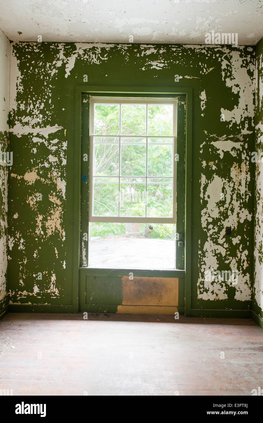 Peeling grüne Wandfarbe im leeren Raum mit offenem Fenster Stockfoto