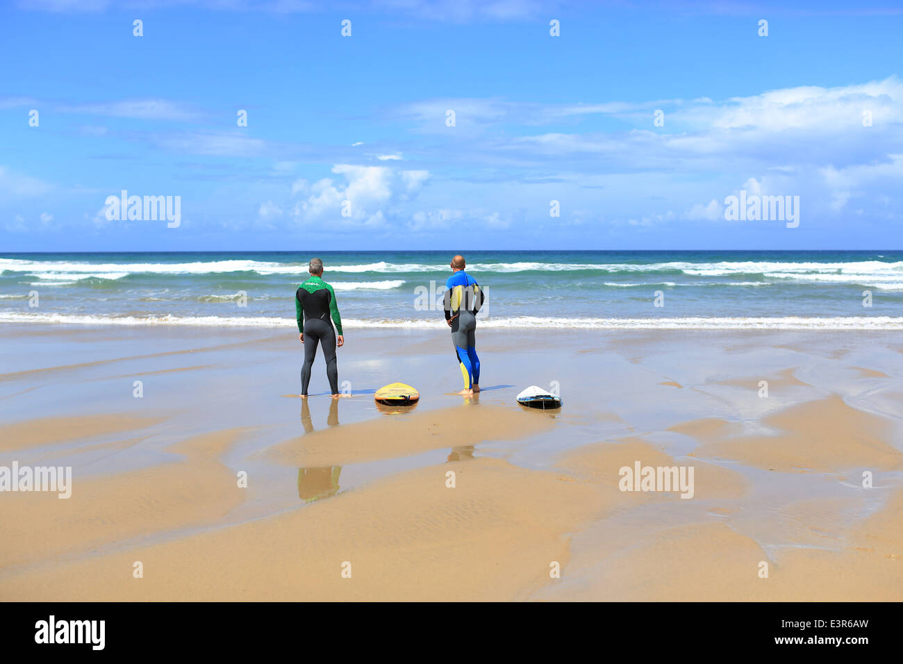 Silver Surfer, zwei mittleren Alter Männer mit Surfbrettern auf einem leeren Strand an einem sonnigen Tag mit blauem Himmel Stockfoto